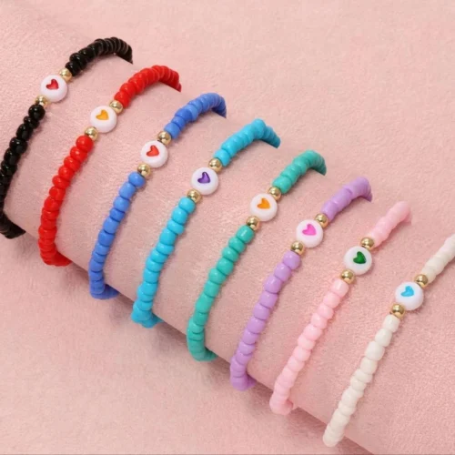 Eight seed bead stretch bracelets in black, red, blue, turquoise, mint, lilac, pink and cream with white heart beads and gold-tone spacers