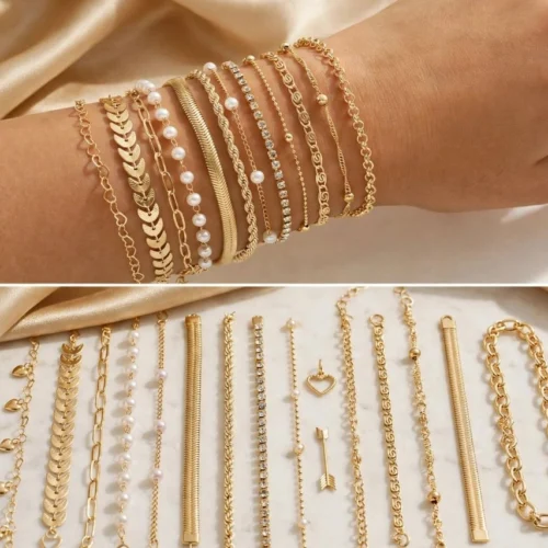 Stack of gold-tone chain bracelets on a wrist and laid out on marble: heart, leaf, paperclip, pearl, snake, rope, rhinestone and chunky chains
