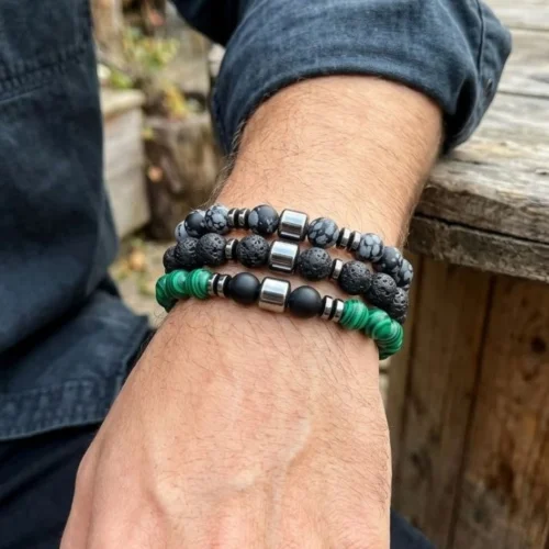 Three men's stretch bead bracelets in grey speckled, black lava-look and green malachite-look beads stacked on a man's wrist