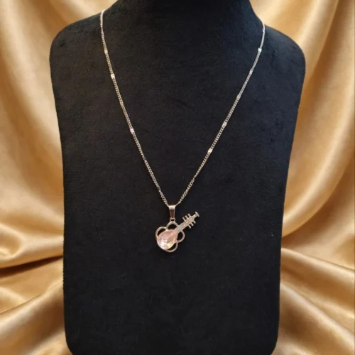 Guitar pendant with pink faceted crystal and rhinestone neck on silver-tone chain on black velvet bust