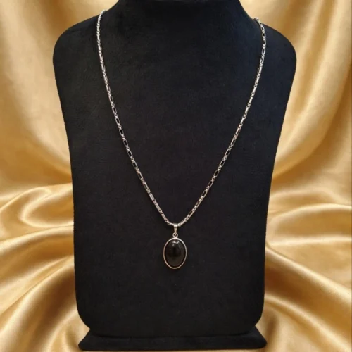 Black oval stone-look cabochon pendant on silver-tone figaro chain displayed on black velvet bust