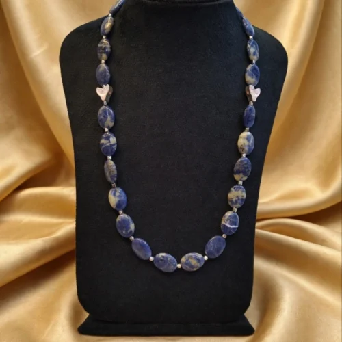 Necklace of flat oval blue and white stone beads with hematite-look spacers and pink accents on black velvet bust