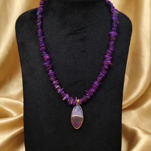 Purple stone chip necklace with banded agate-style slice pendant in gold-tone bezel on black velvet bust