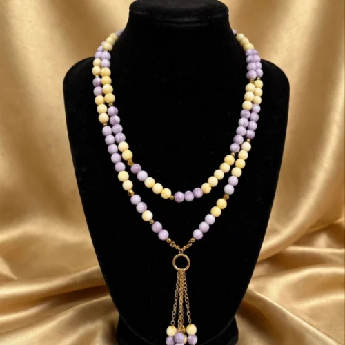 Double-strand lilac and cream yellow bead necklace with gold-tone ring and beaded chain tassel on black velvet bust
