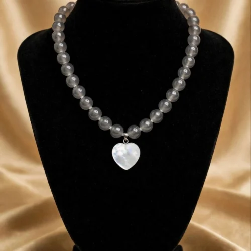 Round grey translucent bead necklace with white shell-look heart pendant on black velvet bust