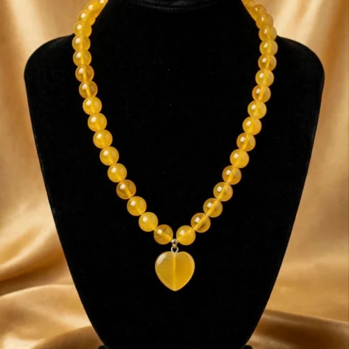 Round honey-yellow translucent bead necklace with matching yellow heart pendant on black velvet bust