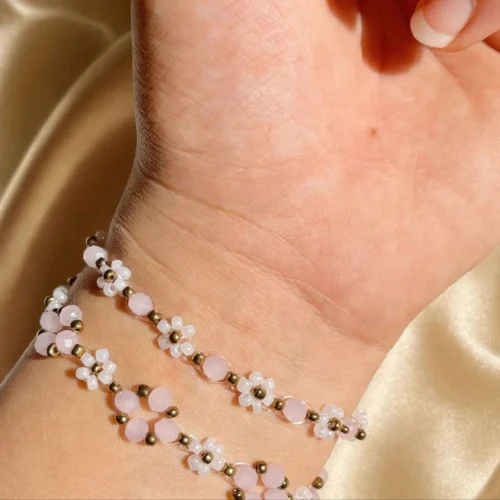 Two pink and white daisy seed bead bracelets stacked on a woman's wrist