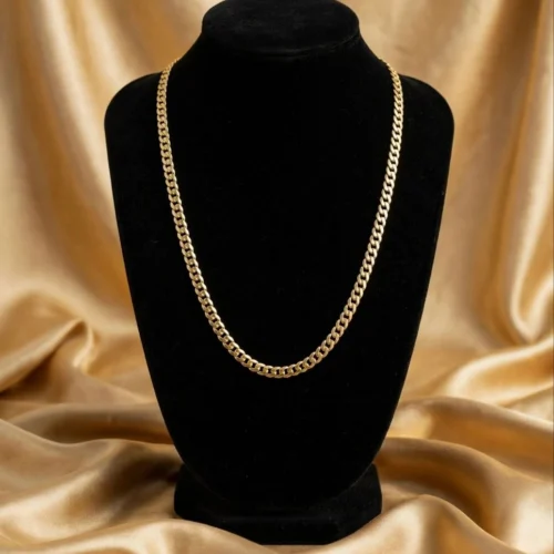 Gold-tone curb chain necklace on black velvet bust in front of gold satin fabric