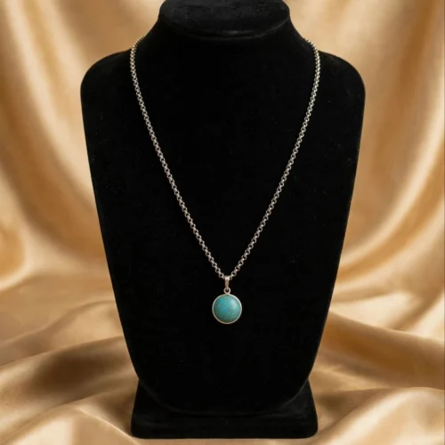 Round turquoise-look cabochon pendant on silver-tone rolo chain displayed on black velvet bust