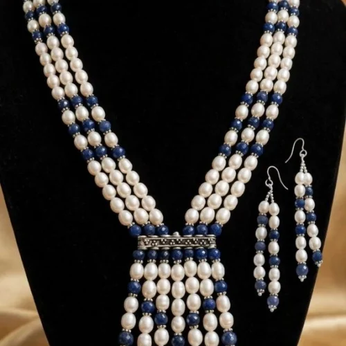 Three-strand faux pearl and navy bead tassel necklace with matching drop earrings on black velvet bust