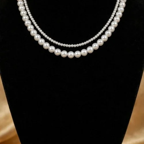 Double-strand white faux pearl necklace with small and large pearls on black velvet bust