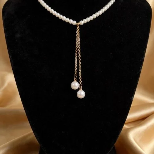 Faux pearl Y-necklace with two gold-tone chain drops ending in larger pearls on black velvet bust