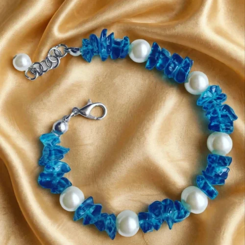 Ocean-blue glass chip and white faux pearl bracelet with silver-tone lobster clasp on gold satin