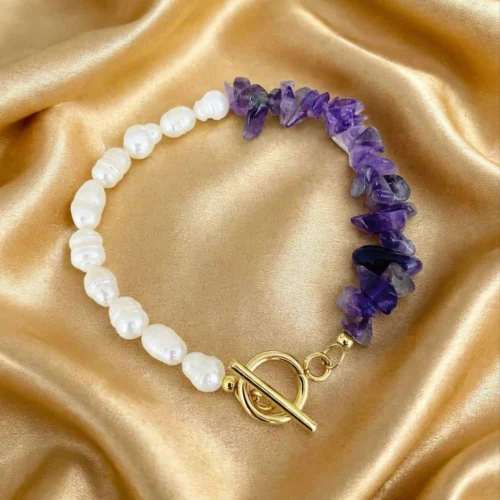 Bracelet of baroque-look faux pearls and purple amethyst-colour chips with gold-tone toggle clasp on gold satin