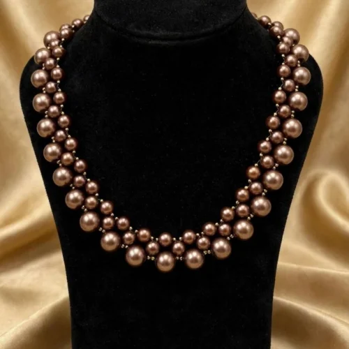 Bronze faux pearl double-row woven collar necklace on a black velvet bust in front of gold satin