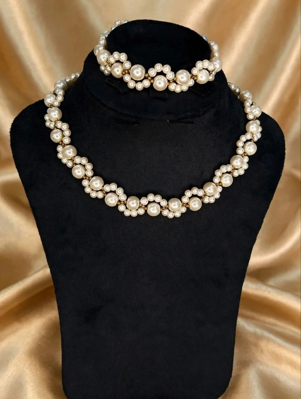 Ivory faux pearl wave necklace with matching bracelet displayed on a black velvet bust
