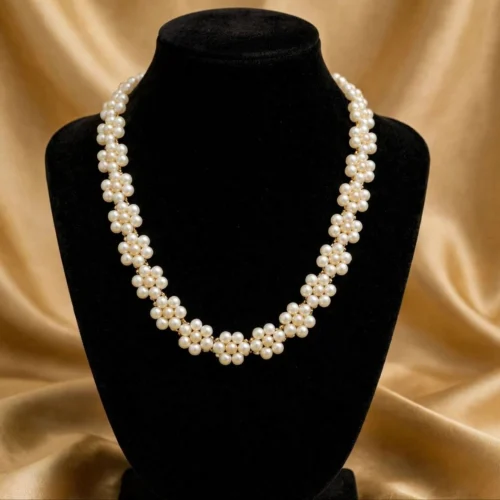 Woven cream faux pearl rope necklace made of small flower clusters on a black velvet bust