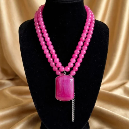 Hot pink double-strand bead necklace with large rectangular pink agate-style pendant on a black velvet bust